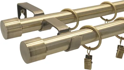 A close-up, angled view of a double curtain rod set with rings and clips, against a white background.