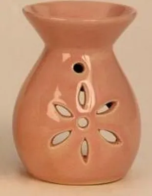 Eine pastellrosa Duftlampe aus Keramik mit bauchiger Form und ausgeschnittenen Design einer Blume.