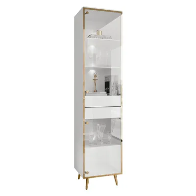 A tall, narrow white display cabinet with glass doors and gold accents, standing on angled gold legs.