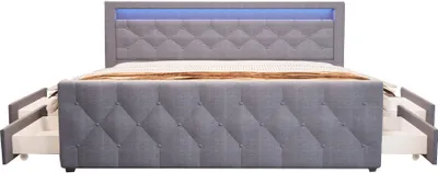 A grey upholstered bed frame with diamond tufting and a blue LED light strip in the headboard. The bed has four drawers pulled out on each side.