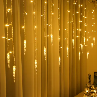 Icicle-shaped LED lights hanging in front of a yellow curtain.