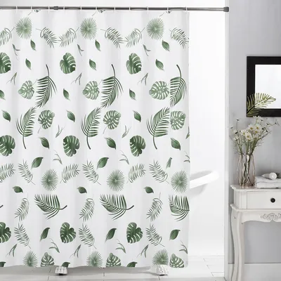 A white shower curtain with a green leaf pattern is hanging in a bathroom.