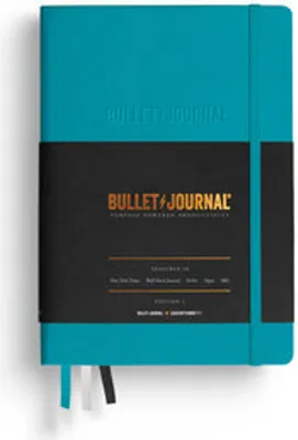 A turquoise bullet journal with a black band around it, showing product details.