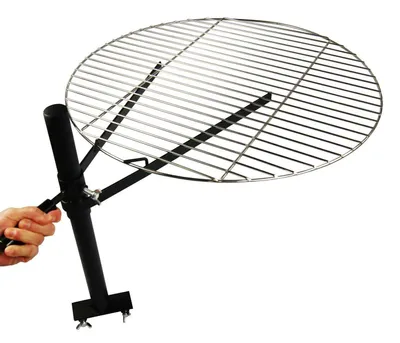 A hand is holding the handle of a black metal grill stand with a circular silver metal grill grate attached, set against a white background.