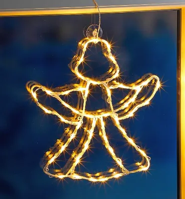 A lighted angel silhouette hanging in front of a blue background.