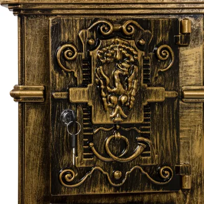 A close-up view of an ornate, antique-style mailbox door with a key in the lock.