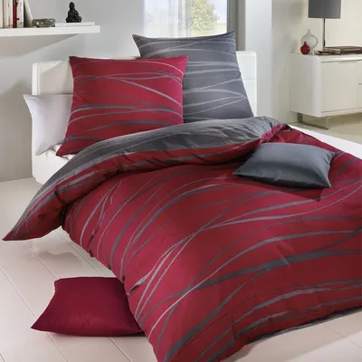A neatly made bed with red and gray patterned bedding.