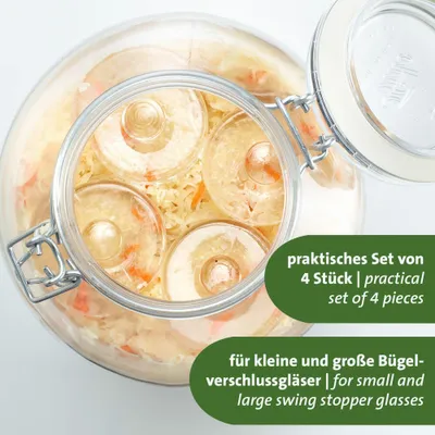 A close-up view of a glass jar filled with fermented food, showing several round glass weights inside.