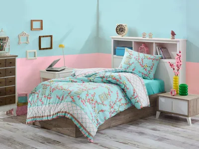 A bedroom scene with a bed made up with a turquoise and pink floral duvet cover and pillow.