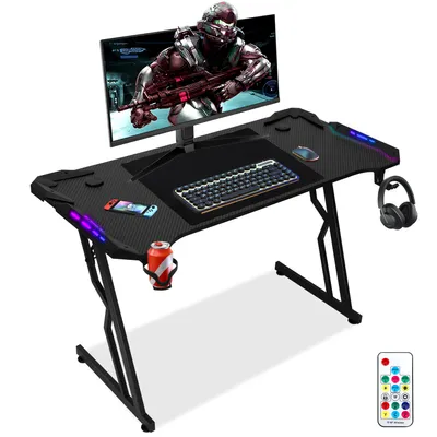 A gaming desk setup with a monitor, keyboard, mouse, headphones, and a drink.