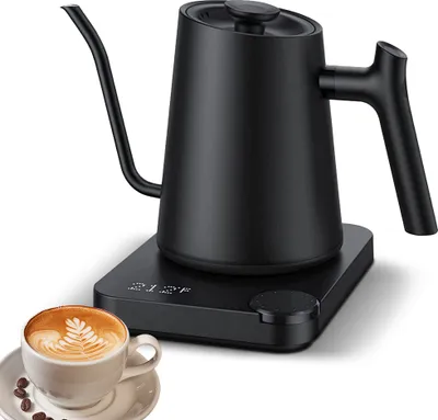 A black electric gooseneck kettle with temperature control sits on its base next to a cup of coffee with latte art.