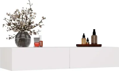 A white floating shelf with decorative items on top, including a vase of flowers and bottles.