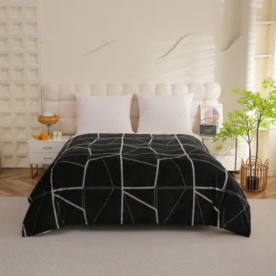 A bed with a black and white geometric patterned blanket.