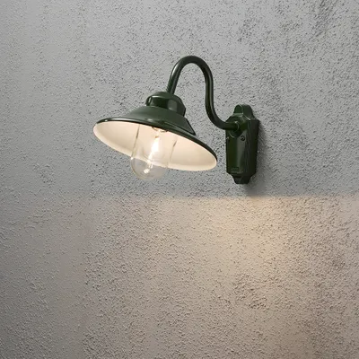 A green outdoor wall lamp mounted on a textured gray wall, with light illuminating the wall below.