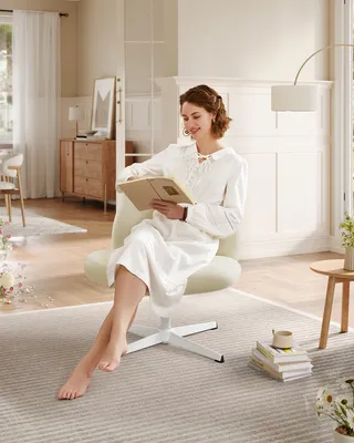 A woman is sitting in a chair reading a book in a well-lit room.
