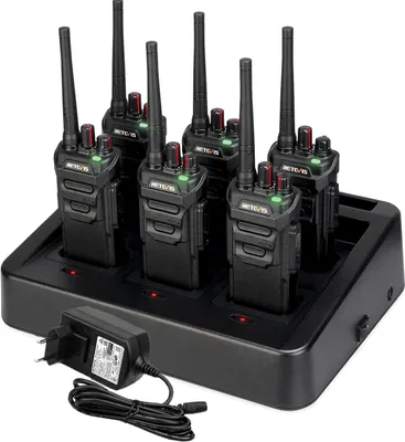 A set of six black walkie-talkies are neatly arranged in a black multi-unit charging station. A black power adapter with a coiled cord is connected to the charging station.