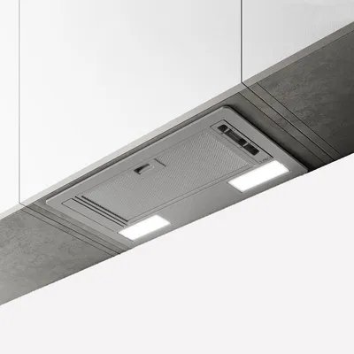 A modern kitchen range hood installed under white cabinets and a concrete-like surface.