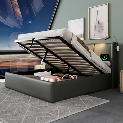 A modern bedroom with a bed that has its storage compartment open, revealing items inside. The bed has a built-in light and charging station.