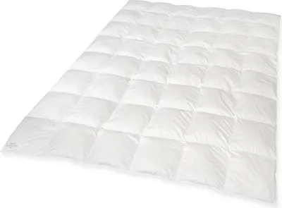 A white quilted comforter is laid out on a white surface, angled diagonally.