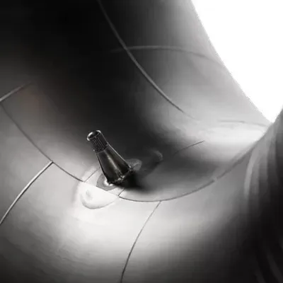 Close-up of a tire valve stem on a black rubber inner tube.