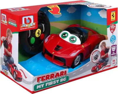 A toy Ferrari remote control car in its retail packaging, with a child playing with the steering wheel controller.