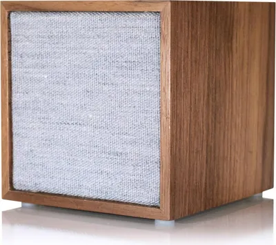 A close-up studio shot of a wooden cube speaker with a fabric front.