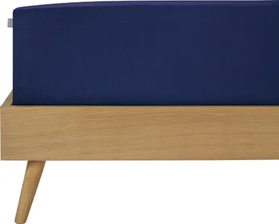 A close-up view of a dark blue fitted sheet on a wooden bed frame.