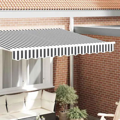 A striped awning is installed above a window on a brick wall, with outdoor furniture visible below.
