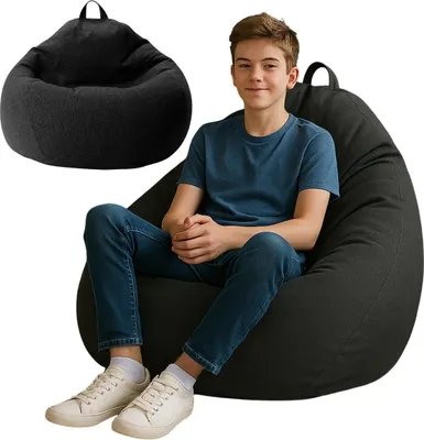 A young boy is sitting on a large black beanbag chair.