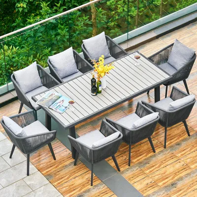 An outdoor patio set with a table and chairs, set on a wooden deck with greenery in the background.