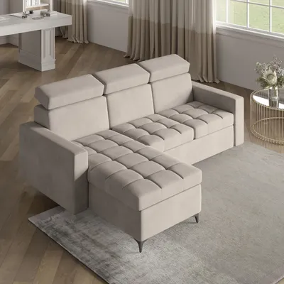 A modern, beige sectional sofa with adjustable headrests and tufted cushions is shown in a well-lit living room setting with wooden floors and sheer curtains in the background.