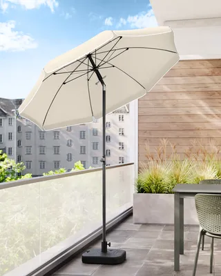 A patio umbrella on a balcony with a table and chair in the background.