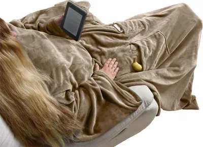 A person is wrapped in a taupe-colored blanket with sleeves, holding a tablet.