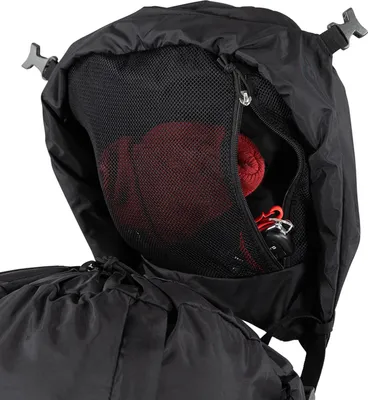 A close-up view of the top opening of a black backpack, revealing a mesh pocket containing a red rolled-up item and a keychain.