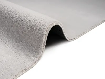 A close-up, angled view of a folded gray rug against a white background.