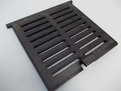 A black cast iron grate with parallel slots is shown on a white background.