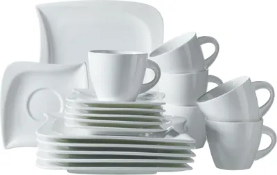 A collection of white ceramic plates and cups are neatly stacked and arranged on a white background.