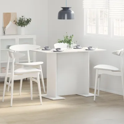 A white dining table with chairs set up in a dining room.