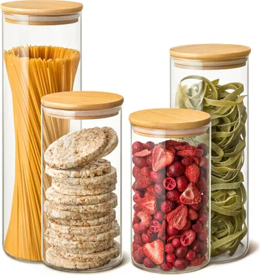 Four glass storage jars with bamboo lids, filled with different food items.
