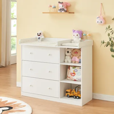 A white changing table with drawers and shelves, decorated with baby toys and accessories.