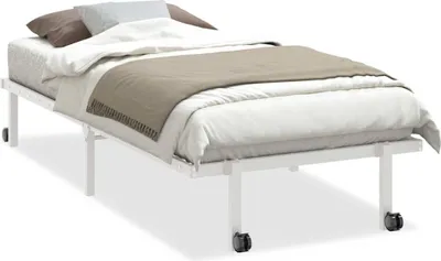 A white metal bed frame with a mattress, white sheets, and two pillows.