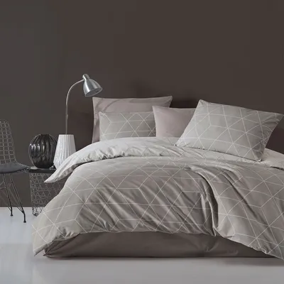 A neatly made bed with geometric patterned bedding in a room with a dark brown wall.