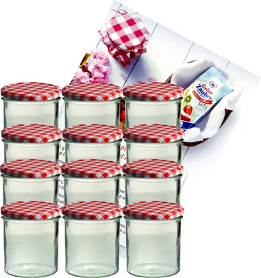 A set of glass jars with red and white checkered lids, arranged in rows, with a small basket containing a packet of jam-making ingredients in the background.