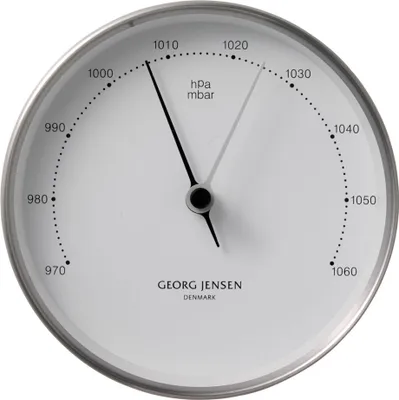 A white barometer with black markings and hands, set in a silver frame.