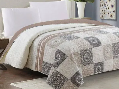 A quilted bedspread is laid out on a bed with white pillows.