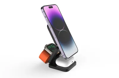 A black charging stand holding a purple iPhone, a silver Apple Watch with an orange band, and white AirPods.