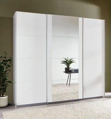 A white wardrobe with mirrored doors in a room with a green wall and a rug.