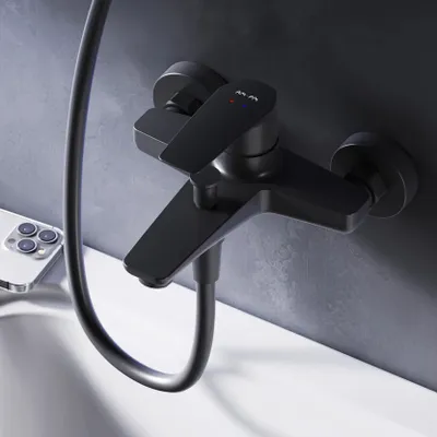 A black bathroom faucet mounted on a dark gray tiled wall, with a white sink visible below. A smartphone is placed on the edge of the sink.