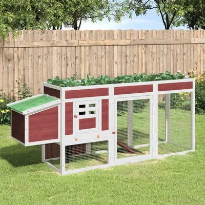 A wooden chicken coop with a green roof sits on a grassy lawn in front of a wooden fence.