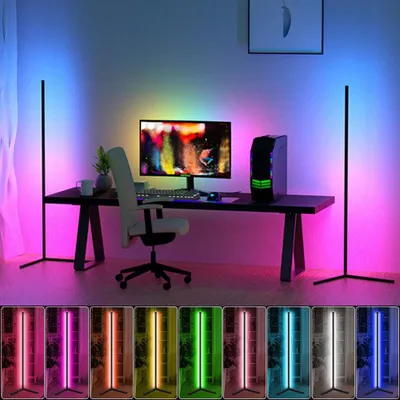 A modern desk setup with a computer, chair, and two corner LED floor lamps casting colorful ambient light.